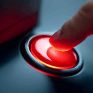 Close-up of a glowing red button being pressed by a fingertip, symbolising an urgent stop, shutdown or big switch-off action.